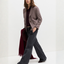 Load image into Gallery viewer, A woman models a houndstooth blazer in brown and beige, paired with dark charcoal flared jeans, a burgundy polo shirt, and a burgundy scarf, set against a clean white studio background.
