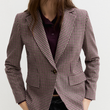 Load image into Gallery viewer, A woman wearing a tailored blazer with a small-scale red and white gingham pattern, layered over a dark purple polo shirt, against a plain light gray background.
