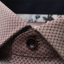 Load image into Gallery viewer, Close-up of a patterned dress shirt collar with a dark brown button, featuring a repeating geometric design in brown and beige.
