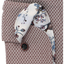 Load image into Gallery viewer, A close-up of a textured brown and beige patterned shirt jacket with a white necktie featuring a blue and purple floral print, secured with a dark brown button.
