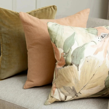 Load image into Gallery viewer, Three decorative throw pillows arranged on a light gray sofa: a textured mustard green pillow, a solid dusty peach pillow, and a large square floral pillow with oversized beige, green, and peach leaves.
