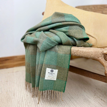 Load image into Gallery viewer, Green plaid blanket draped over a wooden chair with a visible brand label.
