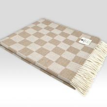 Load image into Gallery viewer, Beige and white checkered throw blanket with a brand label on a light gray background
