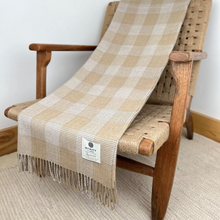Load image into Gallery viewer, A beige and cream buffalo check plaid throw blanket with fringe, draped over a wooden armchair with woven seat and back.
