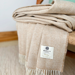 Beige plaid blanket with a brand label on a wooden surface