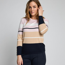 Load image into Gallery viewer, A woman wearing a color-blocked knit sweater with horizontal stripes in beige, light pink, white, and navy blue, paired with navy trousers, against a plain light gray studio background.
