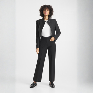 Person wearing a black suit with a white shirt on a light gray background