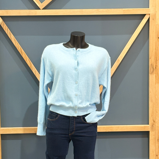 Light blue long-sleeve shirt and dark jeans on a mannequin against a geometric wall.