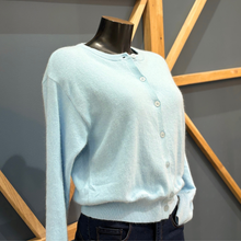 Load image into Gallery viewer, Light blue sweater on a mannequin against a geometric wall design
