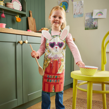 Load image into Gallery viewer, Child wearing a colorful apron with bunny design in a kitchen.

