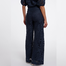 Load image into Gallery viewer, A model shown from the back wearing a navy blue lace top and matching wide-leg trousers with a floral cutout pattern, set against a plain light gray studio background.
