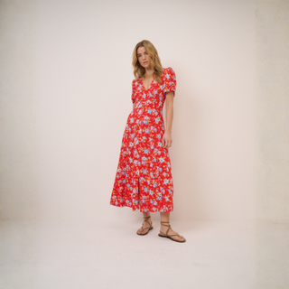 Woman wearing a red floral dress against a plain background