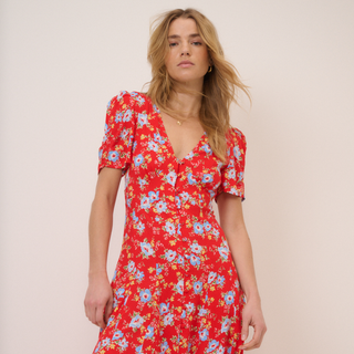 Woman wearing a red floral dress against a plain background