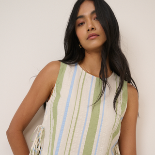 Woman wearing a sleeveless dress with vertical stripes against a plain background