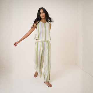 Woman wearing a striped sleeveless top and pants on a white background