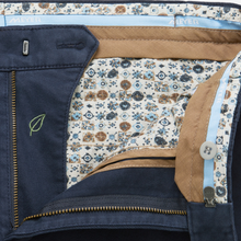 Load image into Gallery viewer, Close-up of a pair of Zieber trousers showing the navy blue outer fabric, a gold zipper, a button closure, and a detailed cream-colored patterned inner lining.

