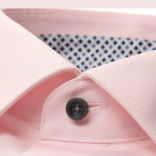 Load image into Gallery viewer, Close-up of a light pink dress shirt collar with a dark button and a blue-and-white patterned inner lining visible behind it.
