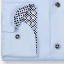 Load image into Gallery viewer, A close-up of a light blue dress shirt with a patterned pocket square tucked into the pocket. The pocket square features a black and white geometric grid pattern with a white border.
