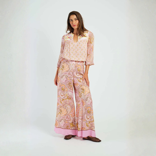 Woman wearing a pink patterned outfit on a white background
