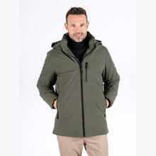 Load image into Gallery viewer, A man wearing an olive green hooded jacket over a black turtleneck sweater and beige trousers, standing against a plain white studio background.
