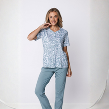 Load image into Gallery viewer, Woman wearing a patterned top and light blue pants on a white background
