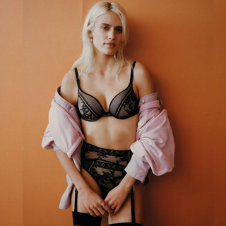 Fashion shot of a women wearing the Passionata Olivia Push Up Bra. Featuring the matching briefs and wearing a light pink jacket shrugged off the shoulder. 