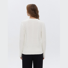 Load image into Gallery viewer, A woman viewed from the back wearing a cream cable-knit sweater and black pants against a plain white studio background.
