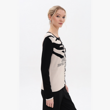 Load image into Gallery viewer, Woman wearing a black and white patterned sweater on a plain background
