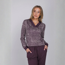Load image into Gallery viewer, A woman modeling a long-sleeve knit top and matching pants set in a studio setting. The top features a dark plum purple and white spiral pattern, paired with solid dark plum purple trim and matching pants.
