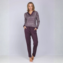 Load image into Gallery viewer, A woman modeling a two-piece loungewear set consisting of a long-sleeve top with a purple and white geometric pattern and matching solid purple drawstring pants, set against a light gray studio background.

