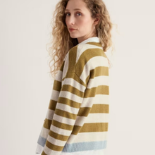 Load image into Gallery viewer, A woman with curly blonde hair wearing a knit cardigan with horizontal stripes in olive green and cream, with a light blue ribbed hem, photographed against a plain off-white background.
