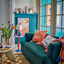 Load image into Gallery viewer, Colorful living room with teal sofa, colorful pillows, and a blue wall.
