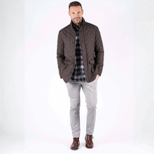 Load image into Gallery viewer, Man wearing a brown quilted jacket over a plaid shirt with light gray pants on a white background
