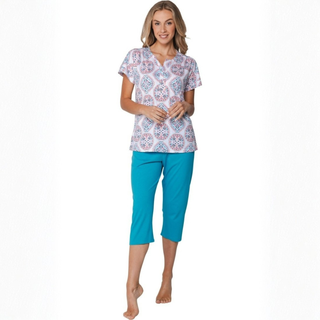 Woman wearing a patterned top and blue capri pants on a white background