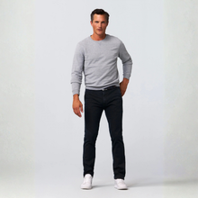 Load image into Gallery viewer, A man modeling a light gray long-sleeve crewneck sweater, dark slim-fit jeans, and white sneakers against a light gray studio background.
