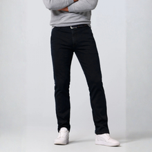 Load image into Gallery viewer, A person wearing slim-fit black jeans, a light gray long-sleeve top, and white sneakers, standing against a light gray studio background.
