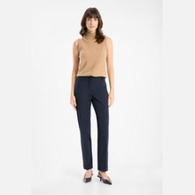 Load image into Gallery viewer, A woman modeling a sleeveless beige knit top and navy blue straight-leg trousers, paired with dark pointed flats, against a plain light gray studio background.
