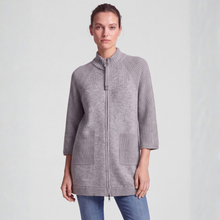 Load image into Gallery viewer, A woman wearing a light gray ribbed zip-front cardigan with a mock neck and front pockets, paired with blue jeans, against a plain light gray studio background.
