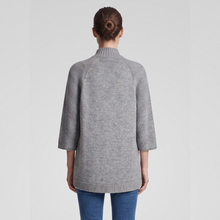 Load image into Gallery viewer, A woman viewed from the back wearing a heather gray mock-neck sweater with ribbed 3/4 sleeves and blue jeans, set against a plain light gray studio background.
