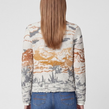 Load image into Gallery viewer, A woman viewed from the back wearing a fuzzy knit sweater with an abstract landscape pattern in cream, orange, and gray, paired with blue jeans against a light gray studio background.
