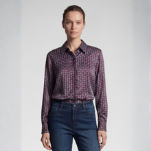Load image into Gallery viewer, A woman modeling a long-sleeve button-up shirt with a dark purple and black geometric pattern, paired with dark blue jeans, against a light gray studio background.
