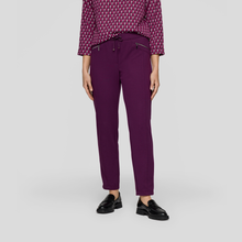 Load image into Gallery viewer, Person wearing purple pants and a patterned shirt on a light gray background

