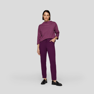 Woman wearing a patterned purple blouse and matching pants on a light gray background