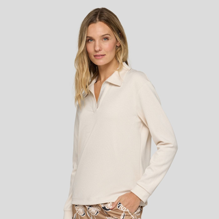 Woman wearing a cream-colored long-sleeve shirt against a plain background