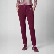 Load image into Gallery viewer, A person wearing burgundy drawstring pants with zippered pockets, paired with a striped long-sleeve top and matching burgundy sneakers, shown against a light gray studio background.
