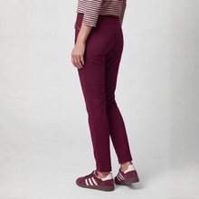 Load image into Gallery viewer, A person shown from the waist down wearing slim-fit burgundy pants, a striped top, and burgundy sneakers with white stripes, photographed against a light gray studio background.
