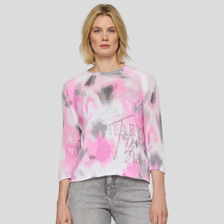 Woman wearing a pink and gray tie-dye shirt with text on a plain background