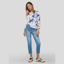 Load image into Gallery viewer, Woman wearing a patterned blouse and blue jeans on a plain background
