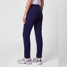 Load image into Gallery viewer, A person shown from the back wearing navy blue slim-fit trousers, a light pink top, and silver and white sneakers against a light gray studio background.
