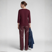 Load image into Gallery viewer, A woman shown from the back wearing a burgundy long-sleeve top and matching burgundy wide-leg pants, holding a blue denim jacket against a light gray studio background.
